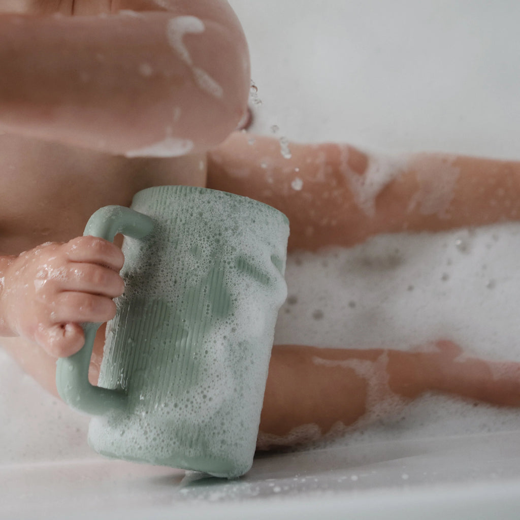 infant using mushie bath rinse cup