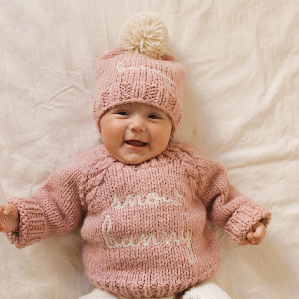 Baby dressed in rosy pink snow bunny pullover and beanie hat 