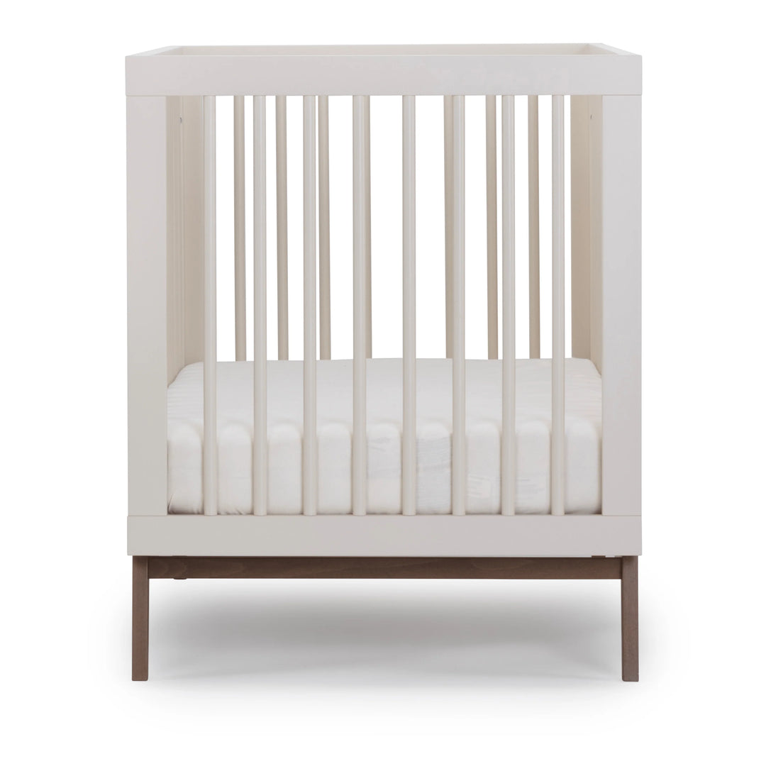 Modern nursery look with the Dadada Soho 3-in-1 Convertible Crib in almond milk walnut shown as a baby crib.