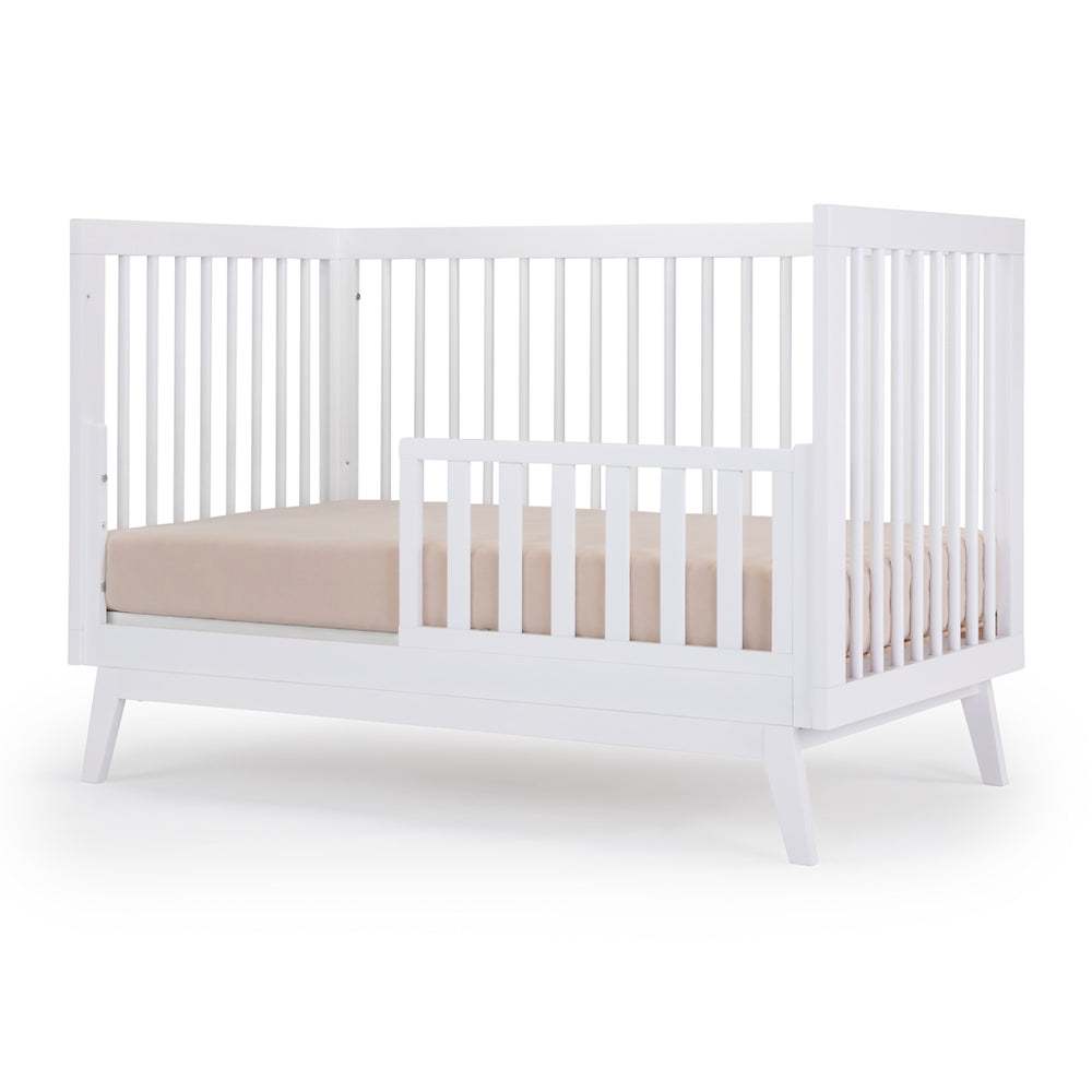 Toddler bed setup of the Dadada Soho 3-in-1 Convertible Crib in all white styled as a crib to toddler bed.