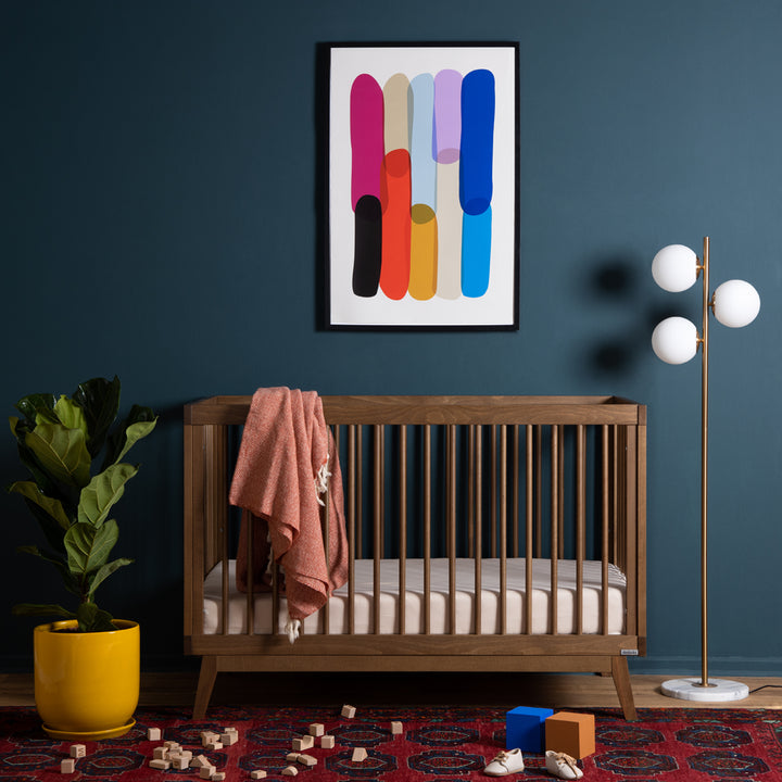 Angled shot of the Dadada Soho 3-in-1 Convertible Crib in walnut finish displayed as a best crib option.