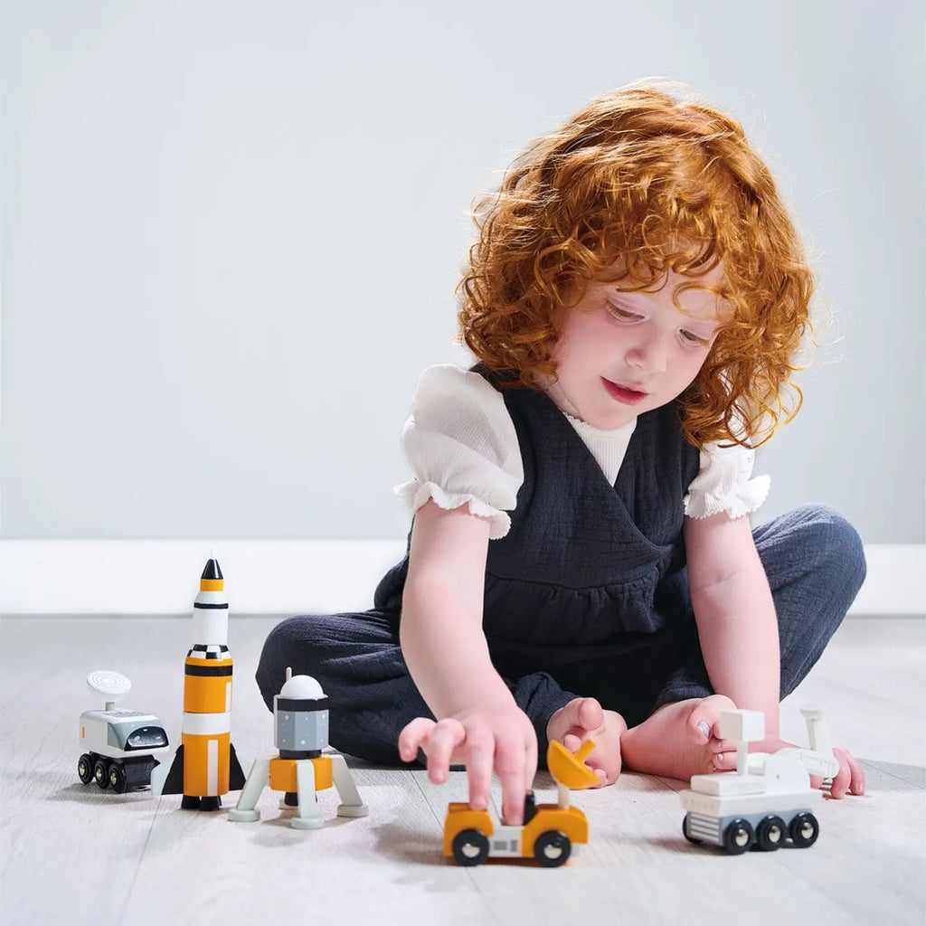 toddler playing with space exploration wood vehicles