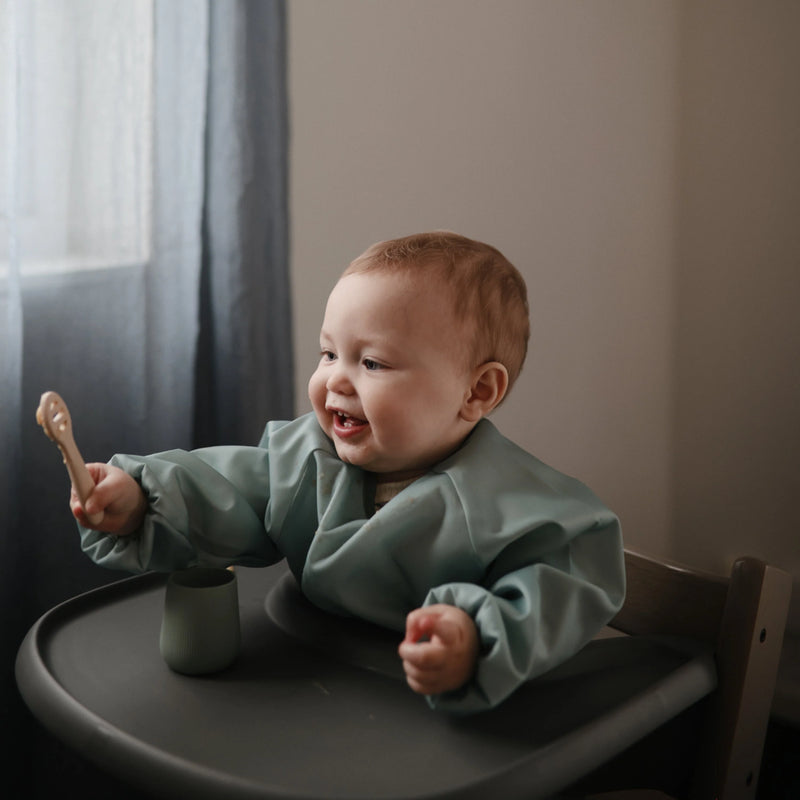 toddler using mushie first feeding spoon