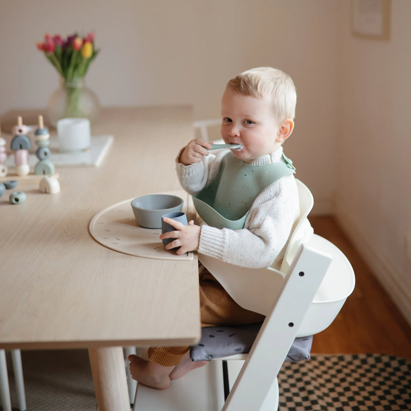 toddler using mushie first feeding spoon