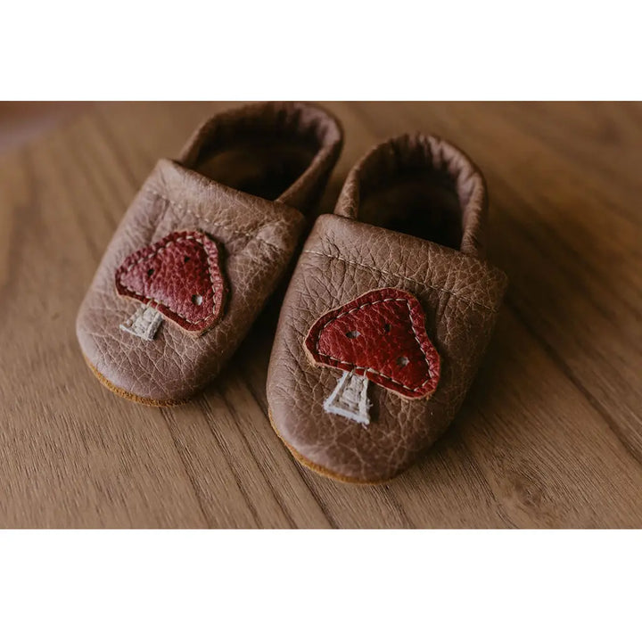 starry night deseng chair brown suede baby shoes with natural red mushroom patch on wooden table 
