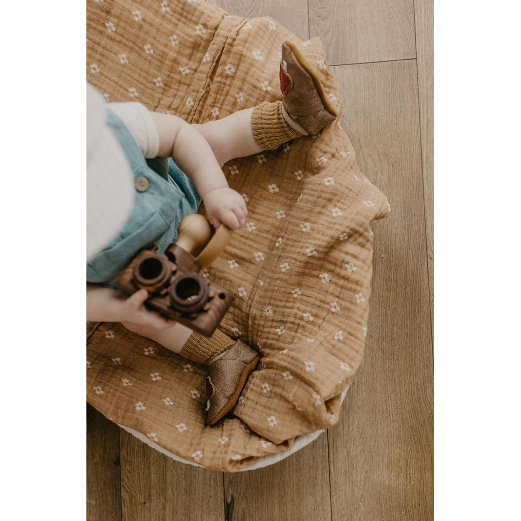baby in linen outfit holding wooden toy and wearing starry knight design baby real leather infant shoes with chai mushroom detail 