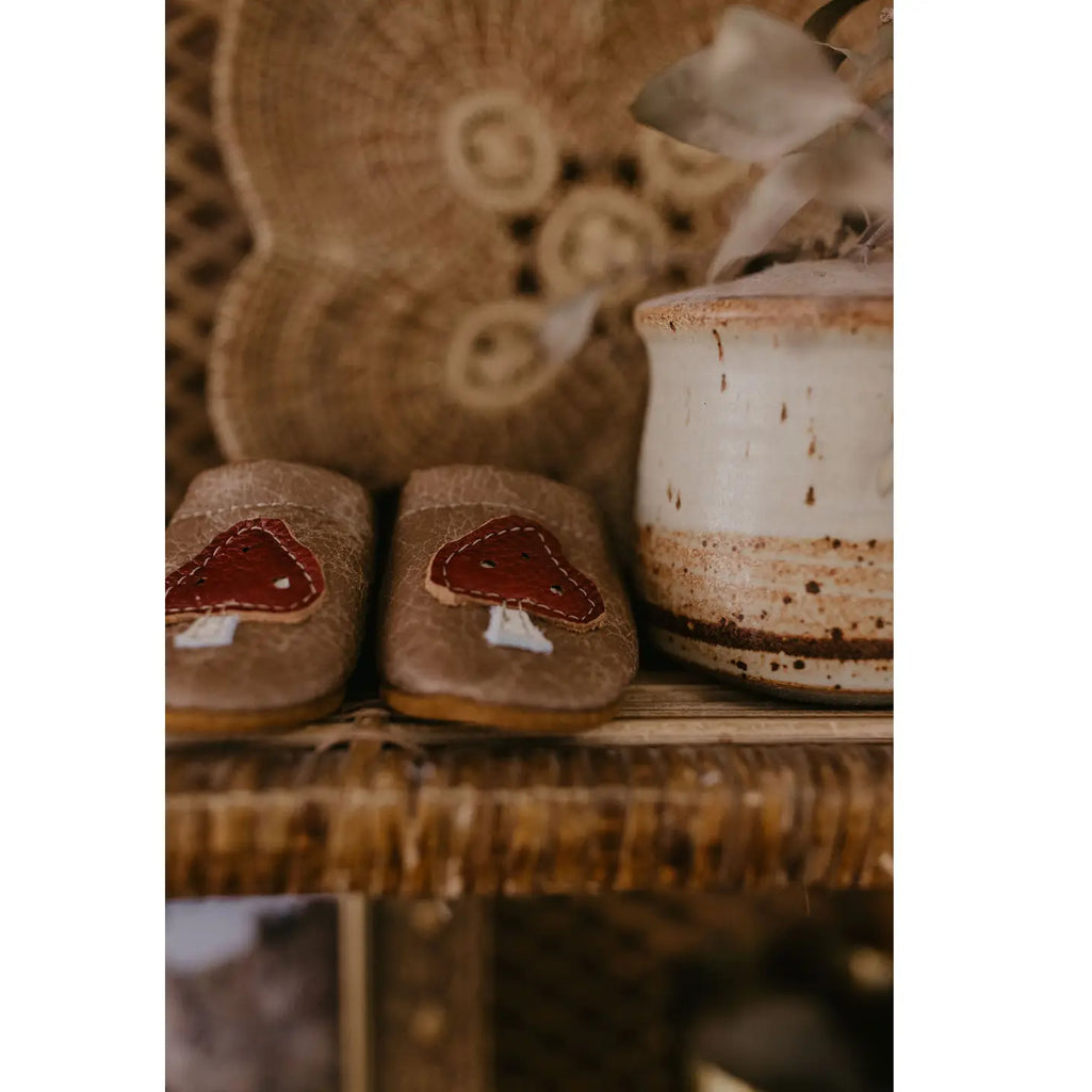 rustic shelf with hand sewn infant leather shoes with cherry red mushroom 
