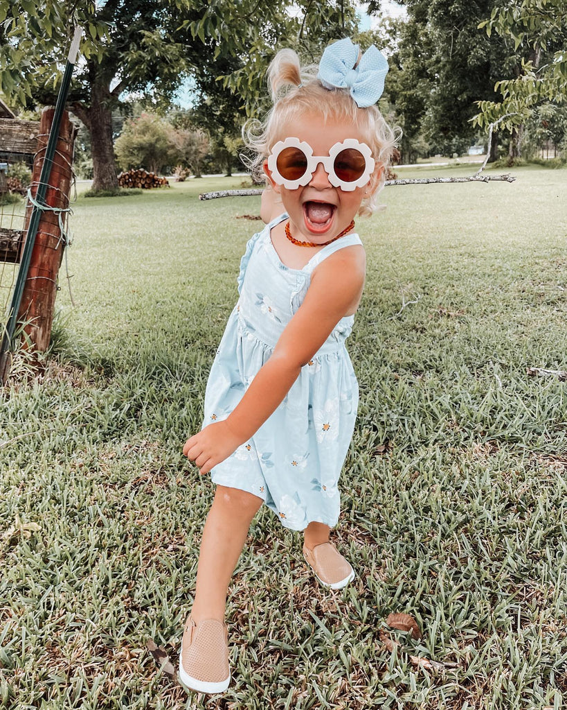 Little girl wearing tan Quinn Little Love Bug co shoes in the grass.