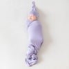 baby swaddled and wearing Kyte Baby purple hat