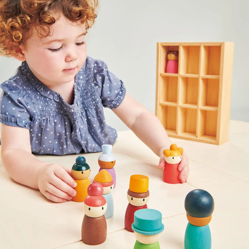 toddler playing with natural wood doll