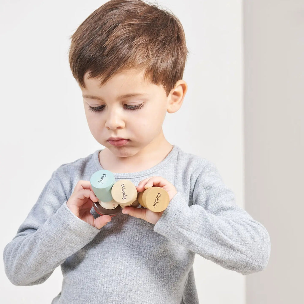 toddler holding natural wood dolls