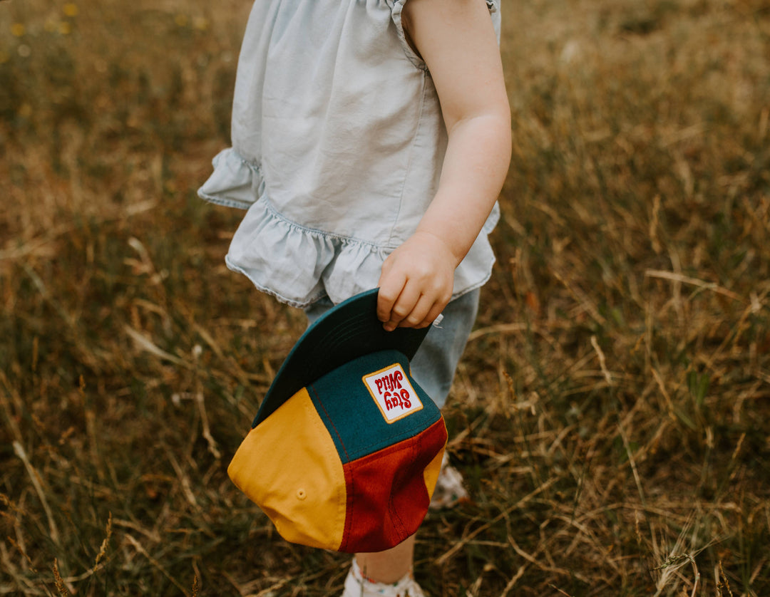 Close up of small hands gripping the brim of this colorful kids hat by Trek Light