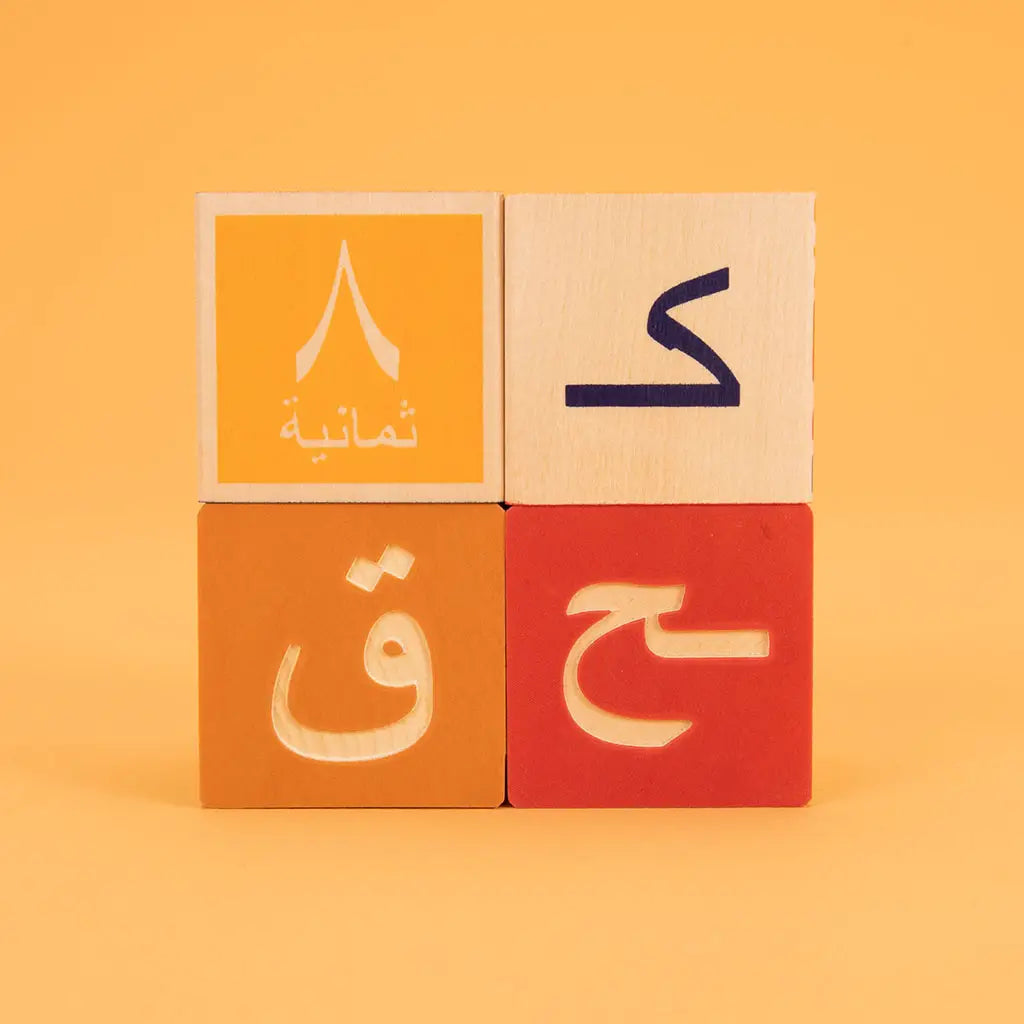 Four wooden toddler blocks showing four consonants of the Arabic alphabet. 