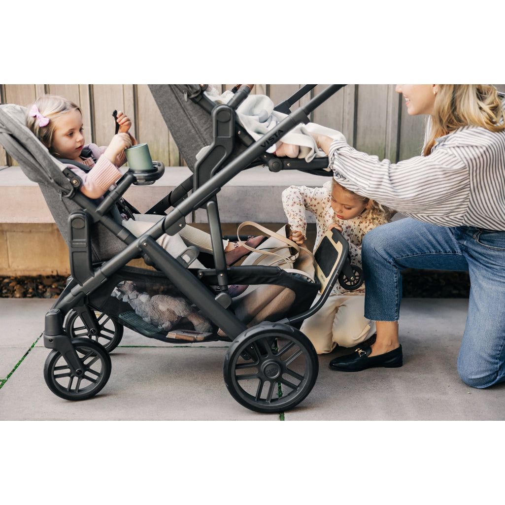 Parents walking with UPPAbaby Vista V3 Twin Double Stroller in a park, dependable lightweight stroller seat model