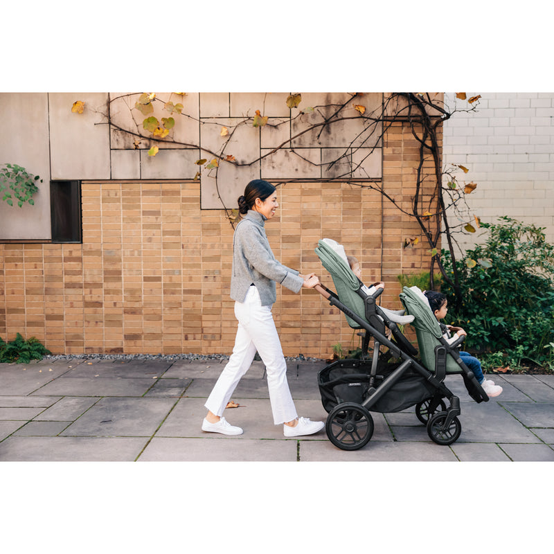 Parents pushing the UPPAbaby Vista V3 Twin Double Stroller with infant and toddler, ideal stroller travel system
