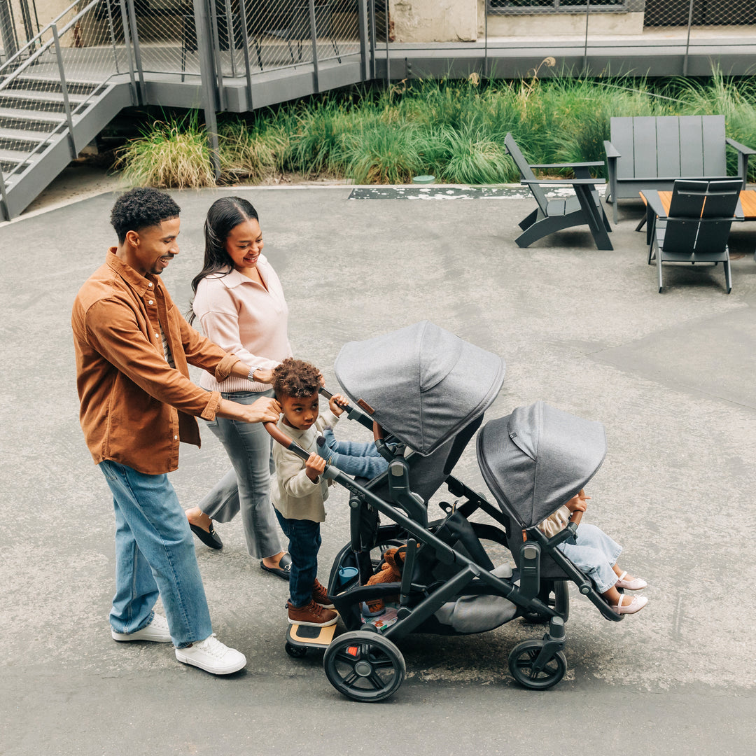 Family with two children and a uppababy v3 vista v3 with rumbleseat v3 double stroller in an outdoor setting