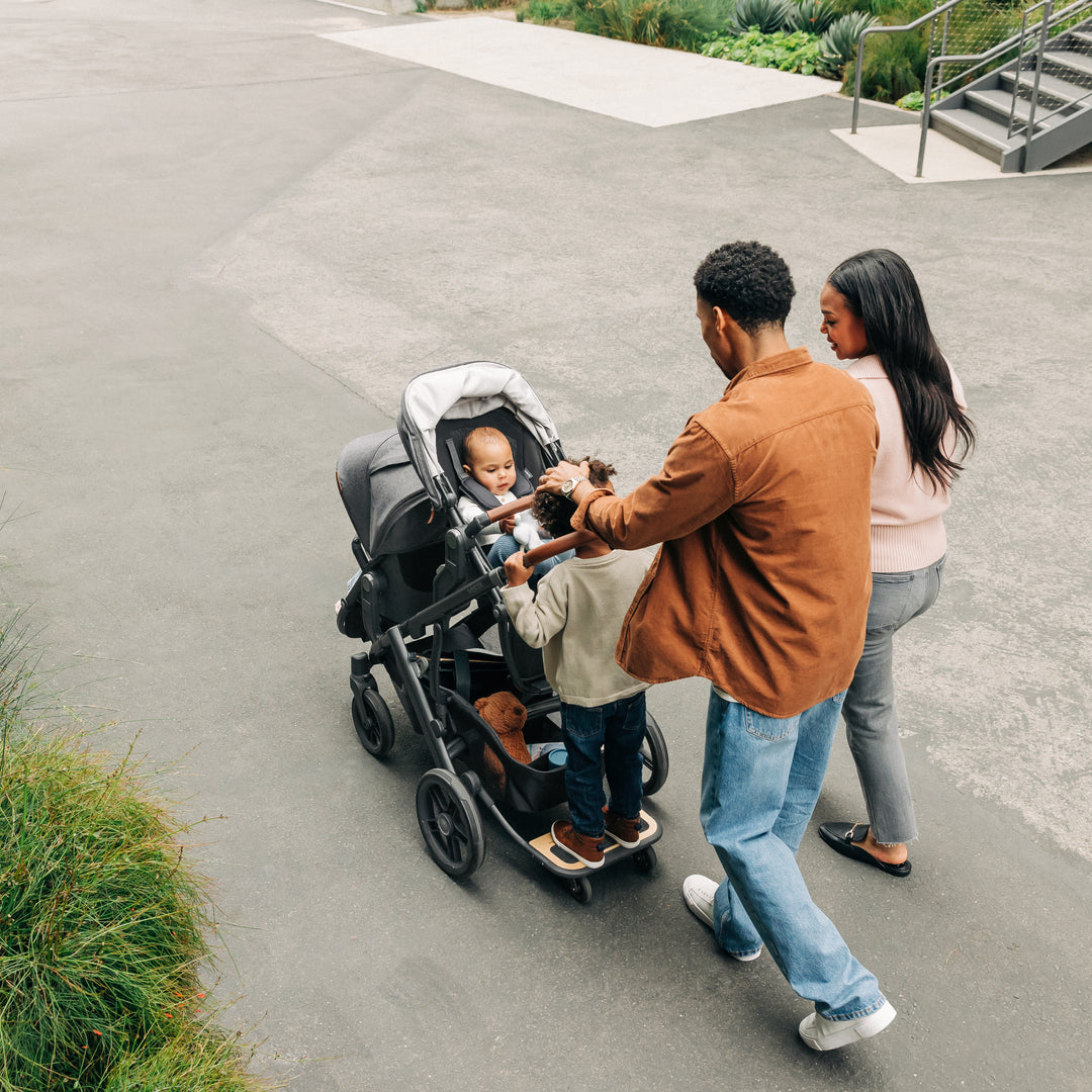 Family with a vista v3 with rumbleseat v3 stroller walking outdoors on a paved path