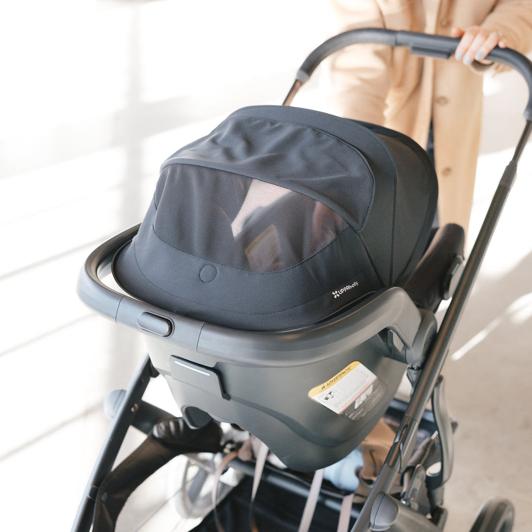 Baby car seat uppababy mesa v3 attached to a uppababy vista v3 stroller with a blurred background