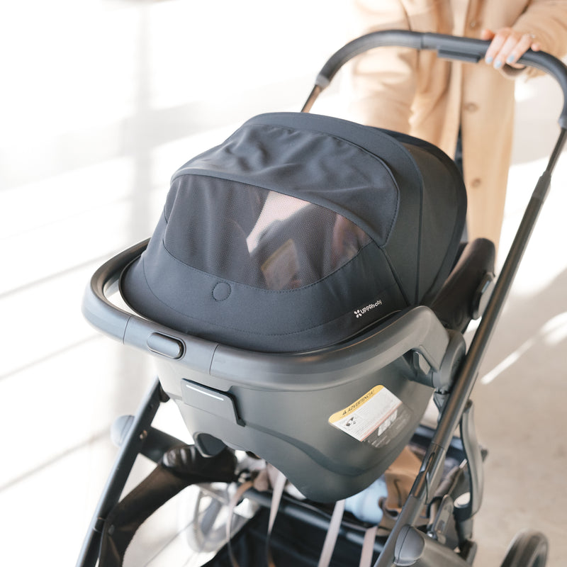 Baby car seat uppababy mesa v3 attached to a uppababy vista v3 stroller with a blurred background