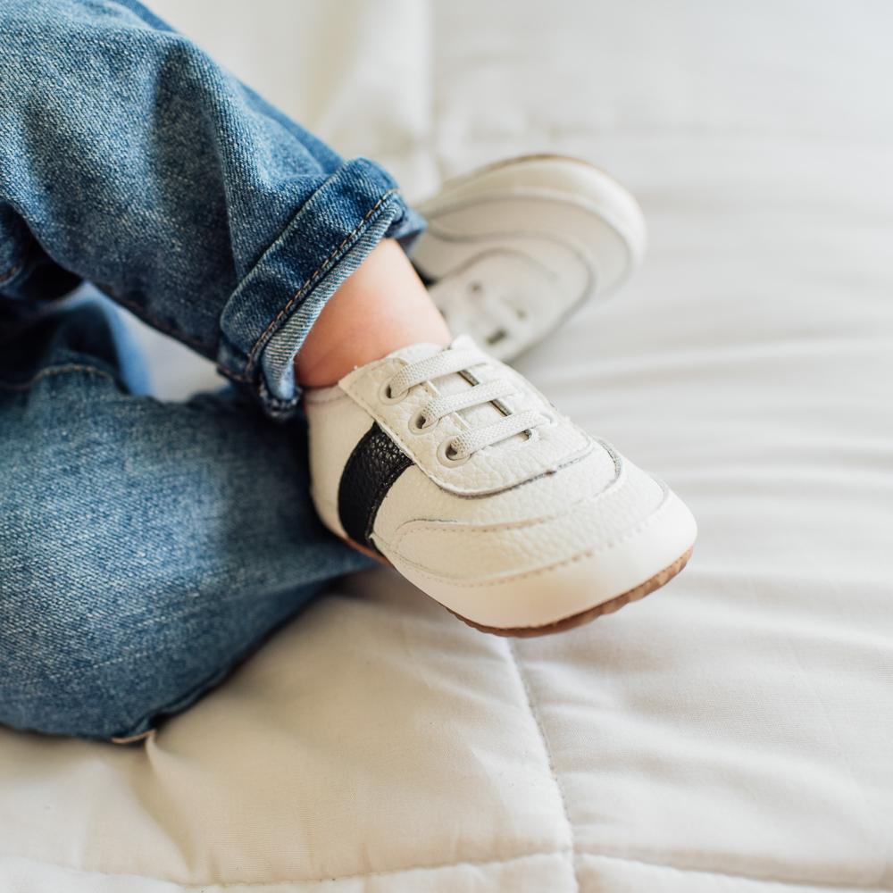 boy wearing white and black little love bug sneakers.