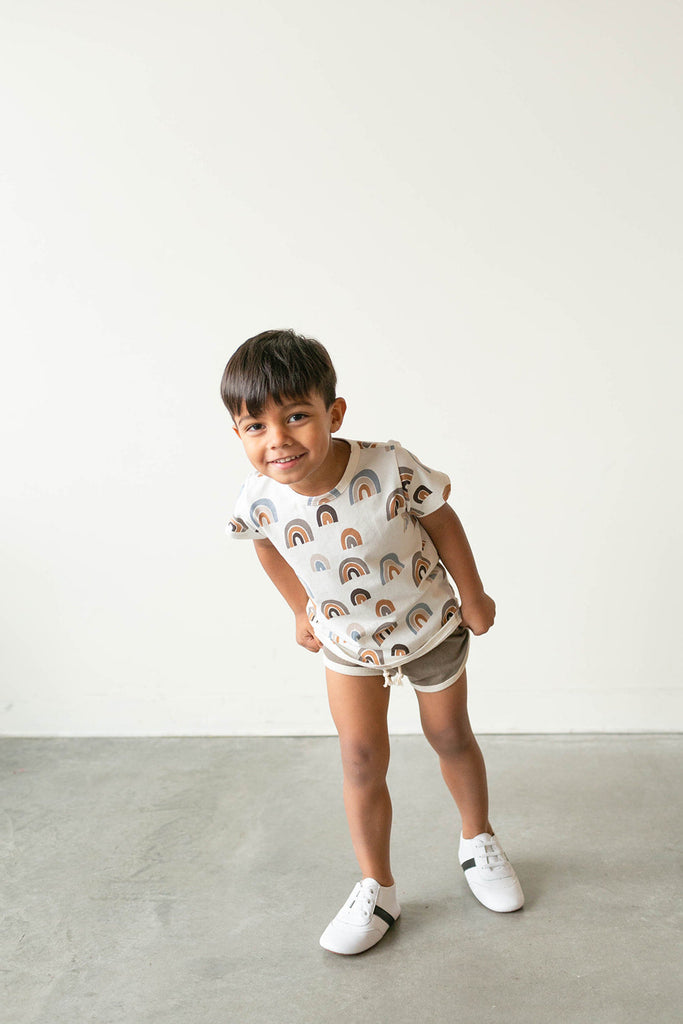 Boy smiling while wearing the white and black little love bug sneakers