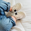 Toddler wearing the leather white and black Little Love Bug sneakers