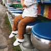 Boy sitting while wearing the white and black little love bug sneakers.