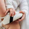 Baby holding a Little Love Bug white and black leather sneaker