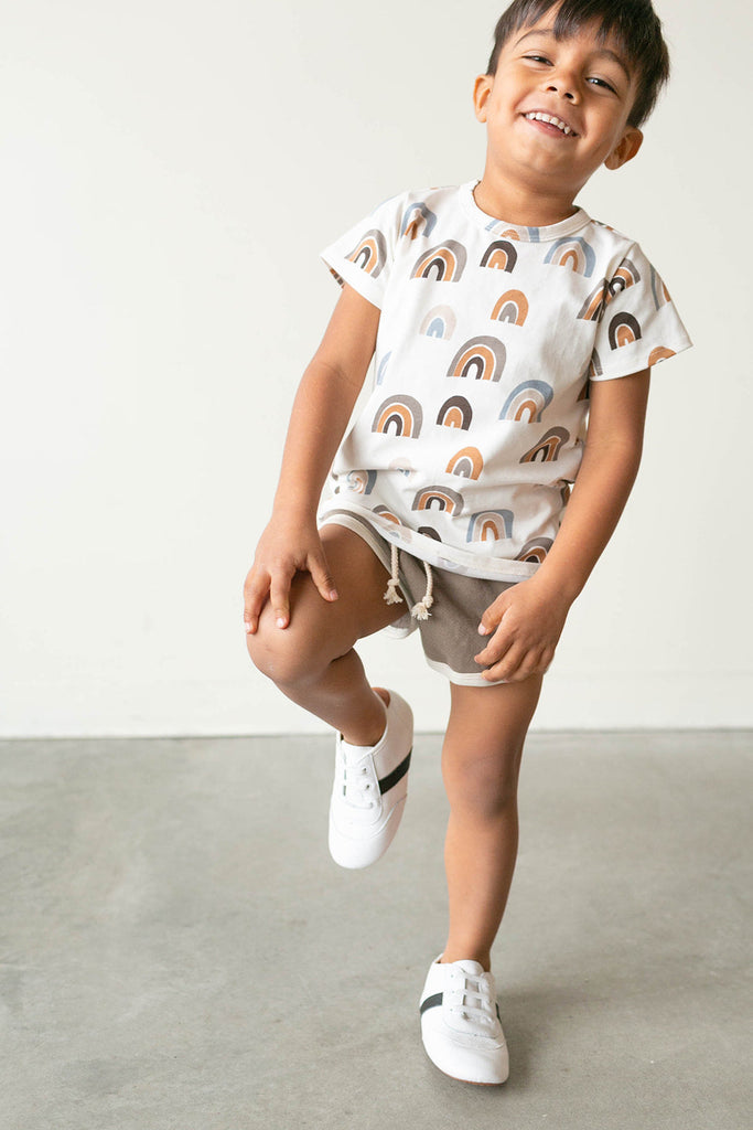 Boy balancing on one foot in the Little Love Bug white and black leather sneakers