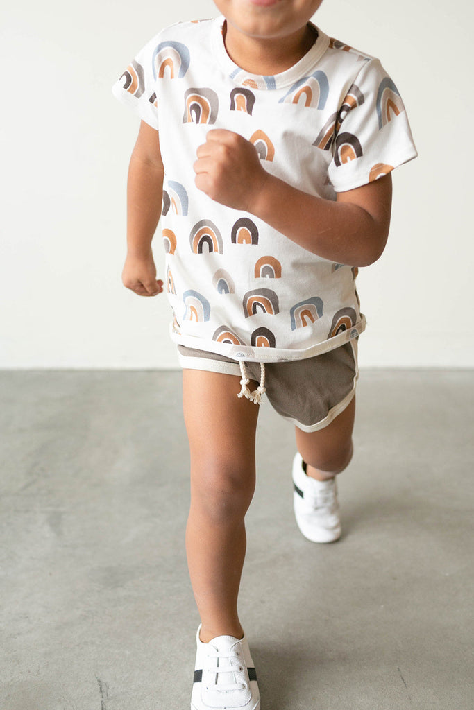 Boy running while wearing the white and black little love bug sneakers