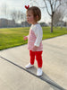 Little girl standing outside, in a pair of white leather slip-on little love bug co shoes.