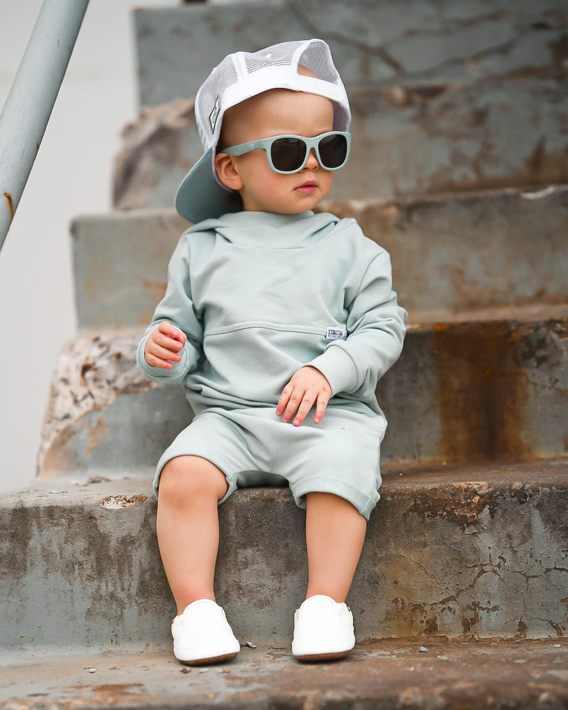 Baby sitting outside while wearing a pair of the white Quinn leather slip on shoes.