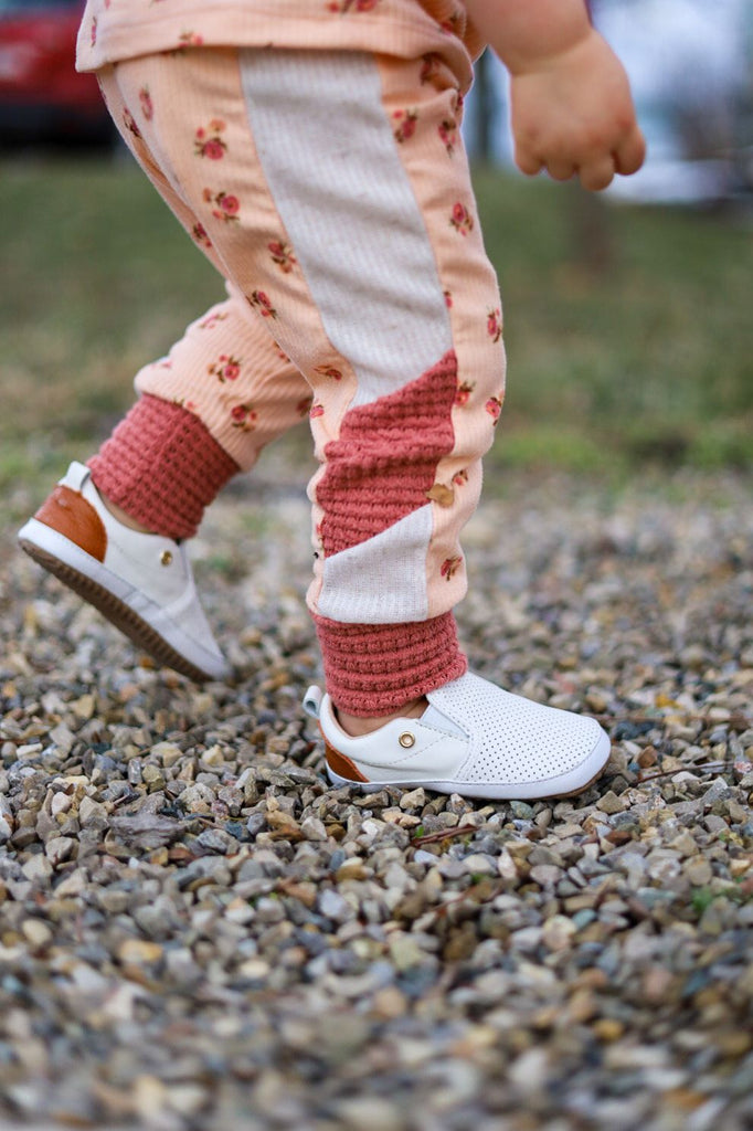 Toddler walking outside in a pair of the White Quinn Little Love Bug Co. shoes.