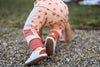 Toddler climbing in a pair of white Quinn leather shoes, made by Little Love Bug co.