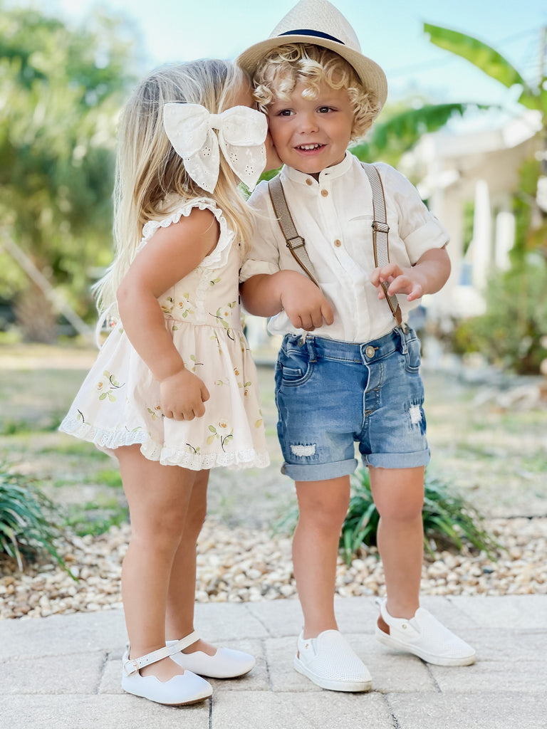 Toddler boy wearing the white Quinn Little Love Bug shoes