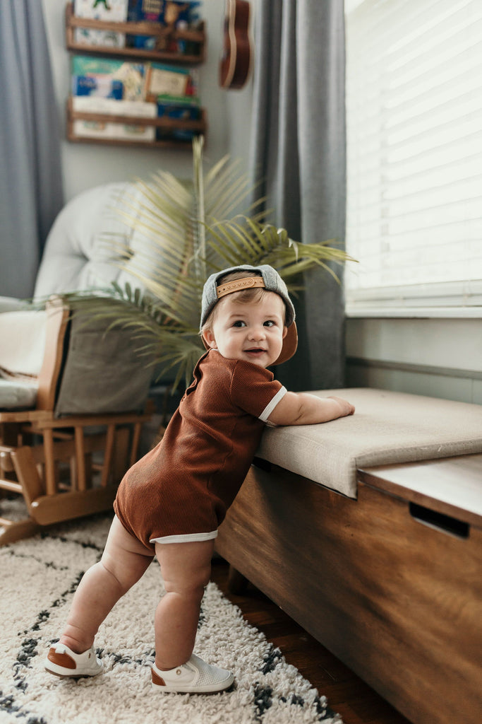 Baby standing while wearing a pair of white quinn leather shoes made by Little Love Bug co.