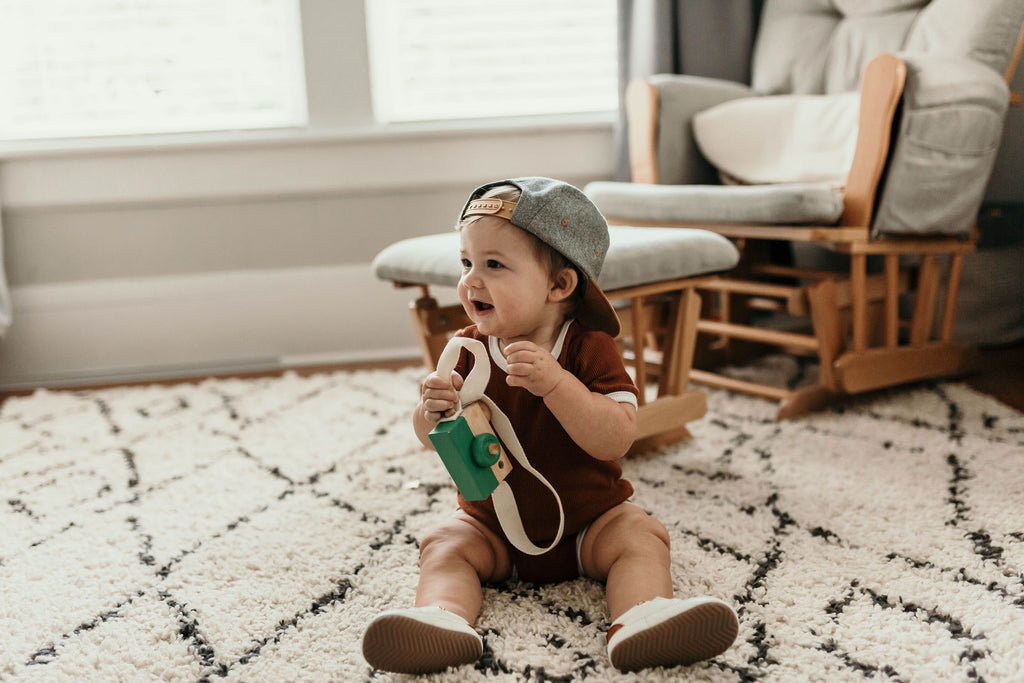 Baby playing while wearing a pair of Little Love Bug Co white quinn shoes.