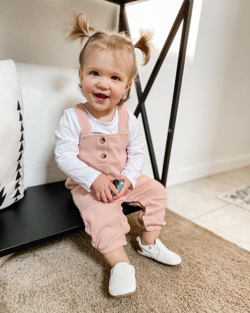 Toddler smiling while wearing a pair of White Quinn leather shoes by Little Love Bug Co.