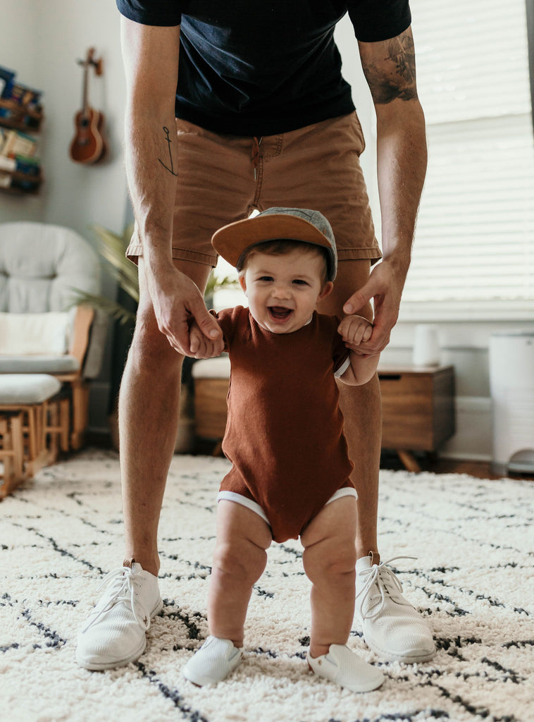 Baby walking inside in a pair of white leather Quinn Little Love Bug co shoes.