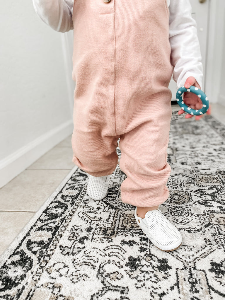 Toddler walking in Little Love Bug Co. White Quinn shoes.