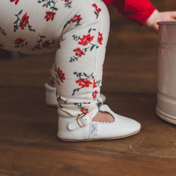 Toddler wearing  Little Love Bug Co. anti-slip white leather t-bar shoes.