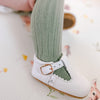 Little girl wearing green socks and leather baby shoes, t-bar white