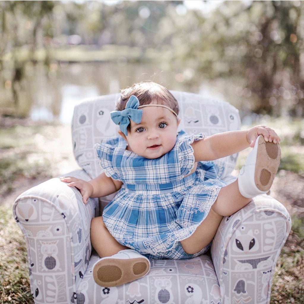 Baby wearing  Little Love Bug Co.'s white t-bar anti-slip shoes.