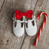 White t-bar little love bug shoes next to a candy cane.