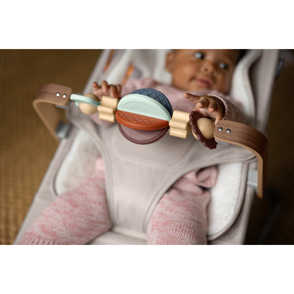 baby playing with toy bar on bouncer