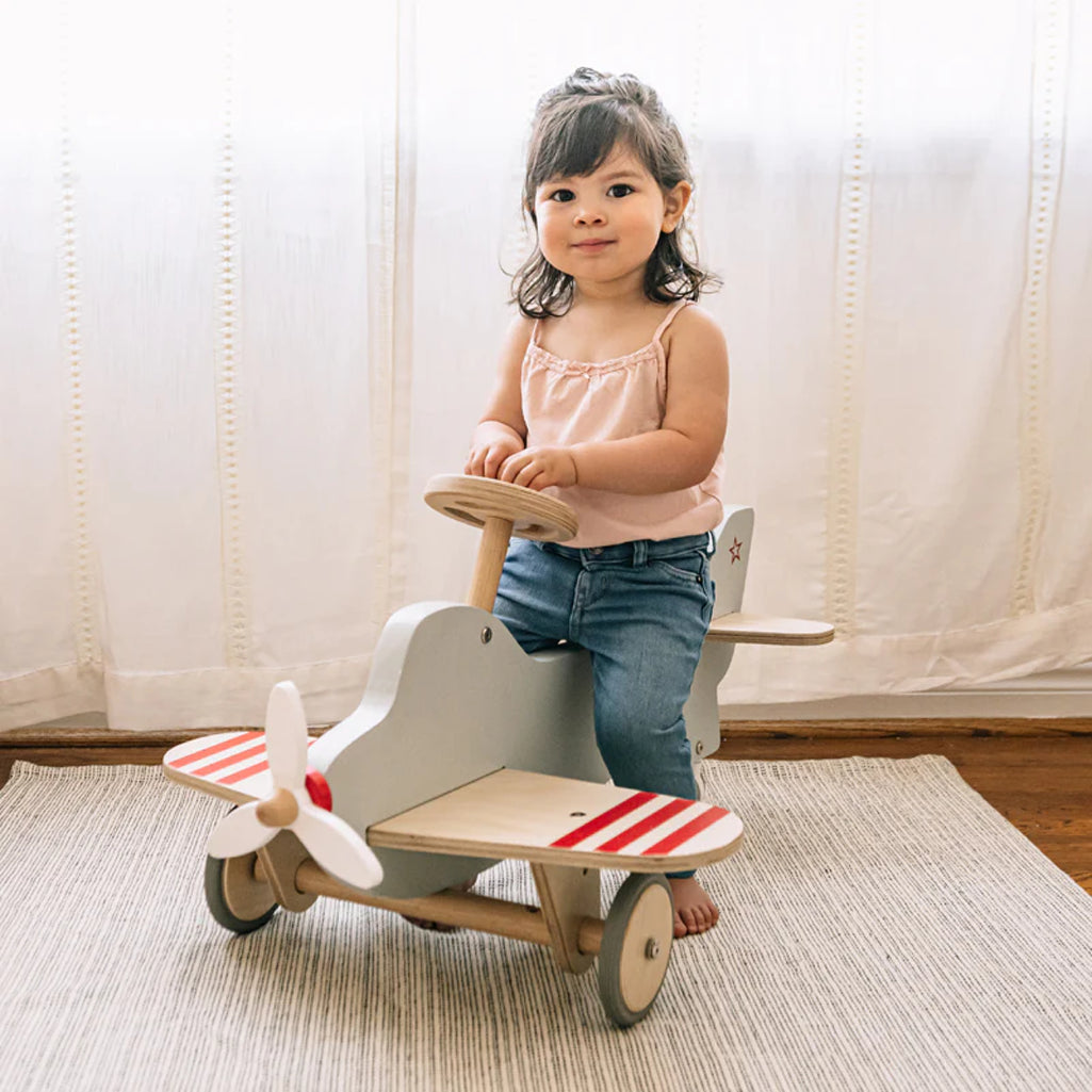 Child sitting on Wonder & Wise Airplane Ride-On Toy, classic wooden airplane rocker for imaginative indoor play