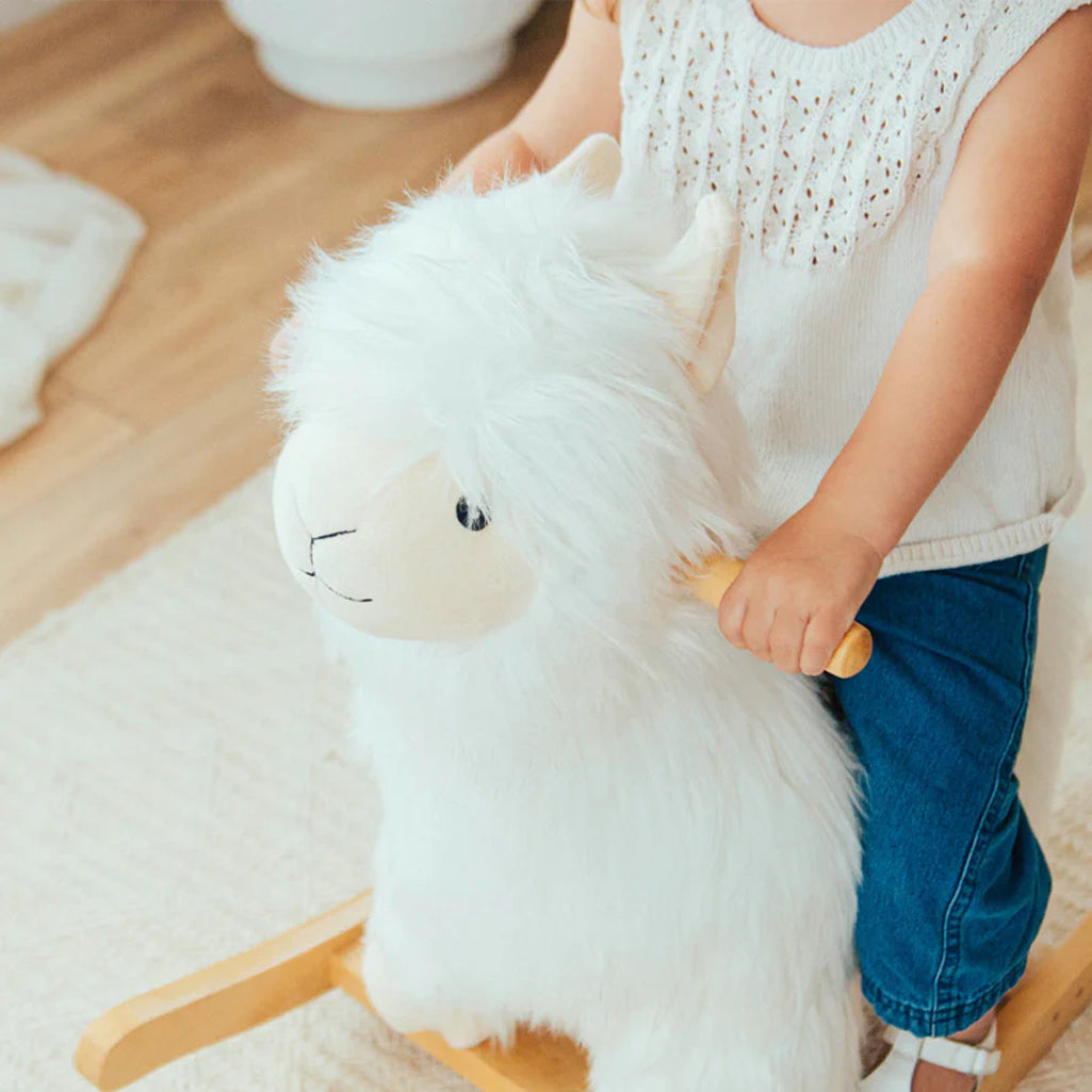 Toddler sitting on Wonder & Wise Alpaca Rocker Toy, cozy plush alpaca rocker for baby nursery dŽcor and active play