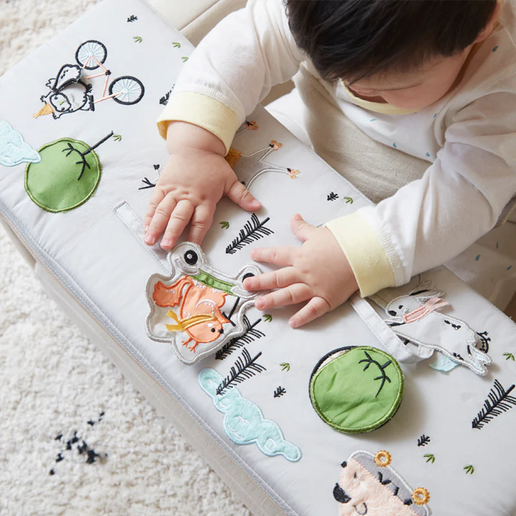 baby playing with wonder and wise nursery chair with activity table attached 