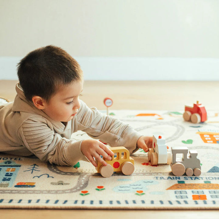 Child playing with Wonder & Wise Around Town Play Mat and wooden vehicles, educational city scene toy for creative learning