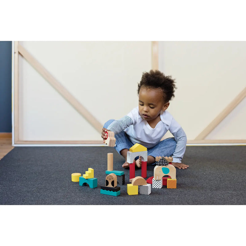 little boy playing with petitcollage animal building blocks wooden town